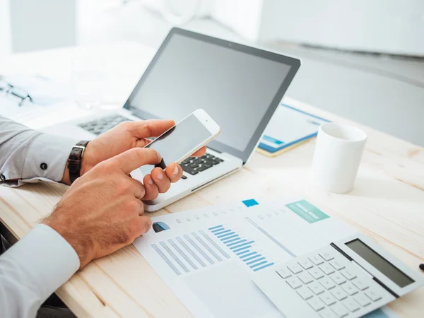 Director checking figures on a phone beside financial statements