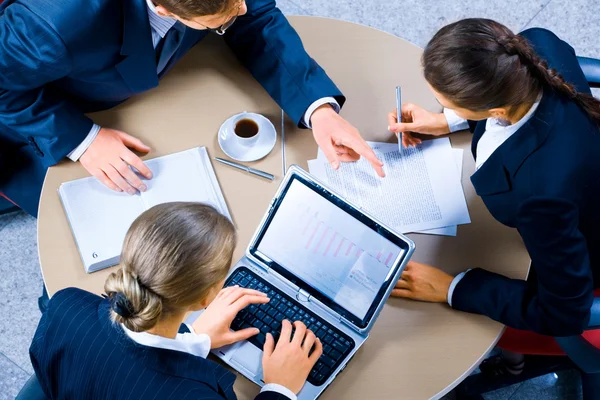 Three colleagues reviewing company performance figures around a table