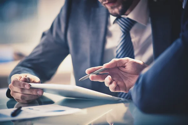 Two advisers reviewing documents together across a meeting table